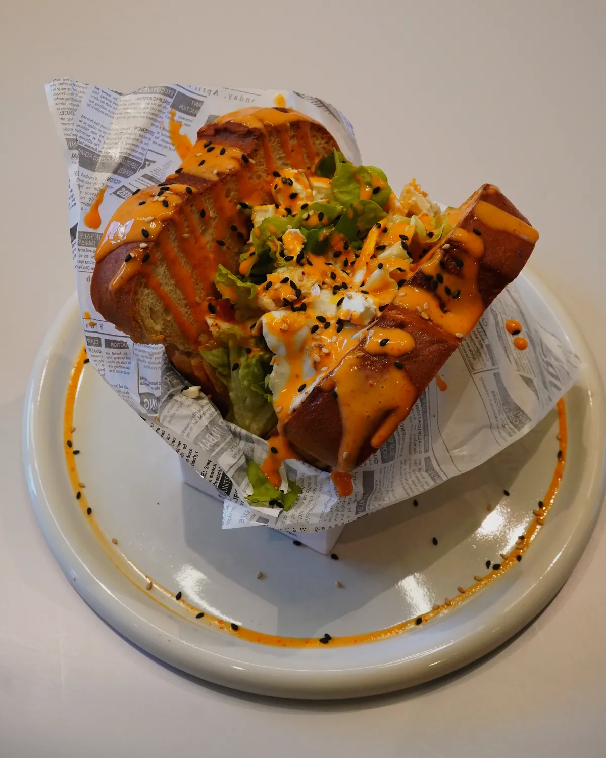 Brioche-Sandwich im Papier auf dem Teller