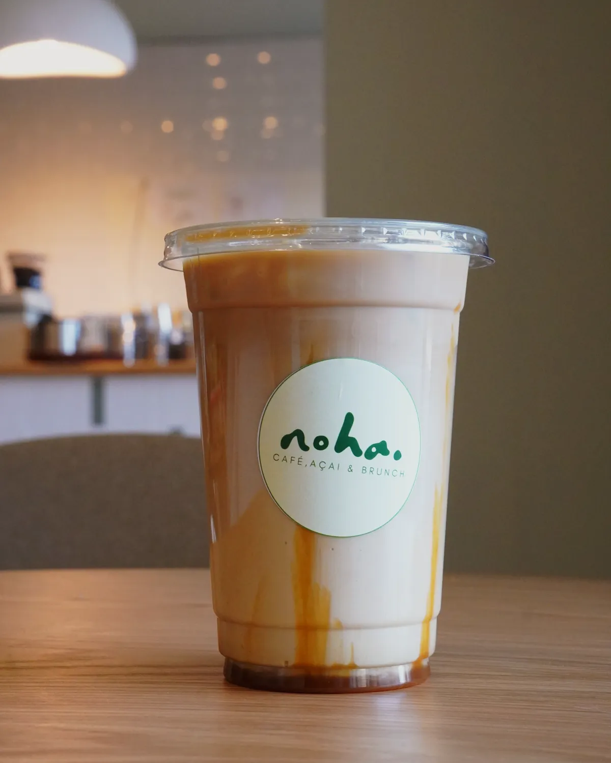 Kaffeegetränk im noha.-Becher auf dem Eichentisch