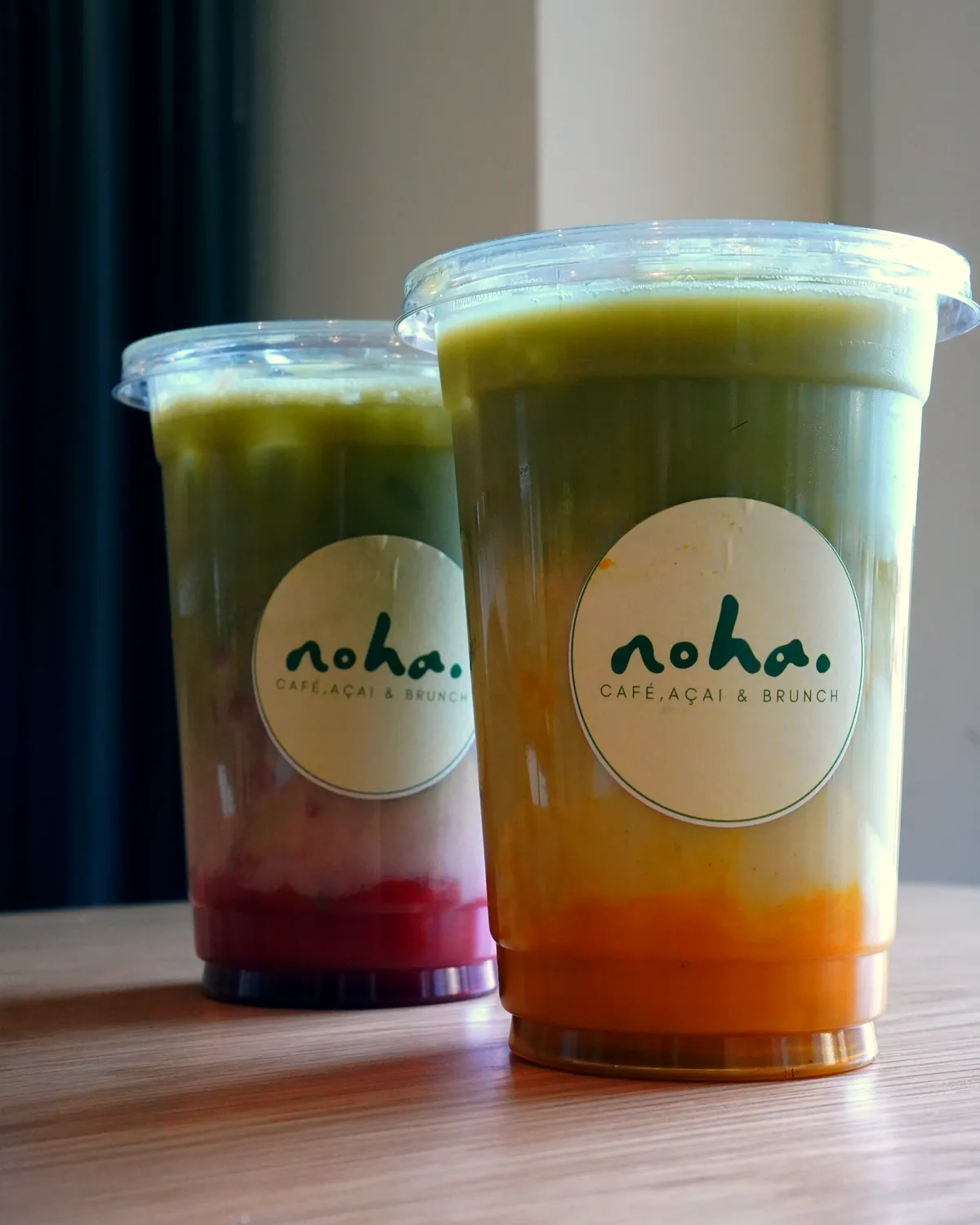 Zwei Iced Matcha im noha.-Becher auf dem Eichentisch